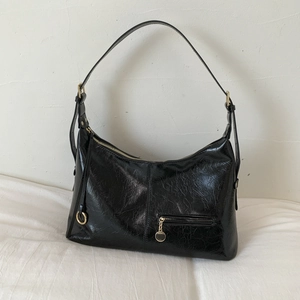Detail of vintage black high-gloss crescent bag with gold-tone zipper and textured finish