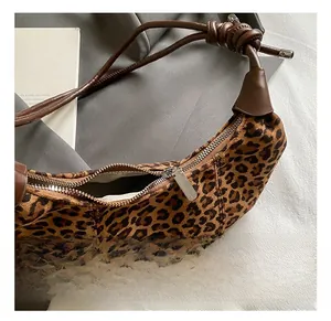 Detail of leopard print crescent bag featuring a knotted leather strap and silver hardware