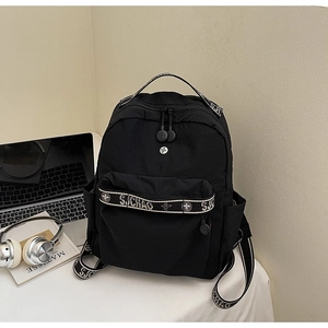 Detail of black casual backpack with front pocket, side pockets, and modern lettering strap