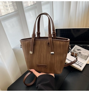 Detail of woven texture and leather strap on brown tote bag with fashion label