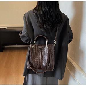Detailed view of dark brown woven leather bucket bag with gold-tone hardware and strap