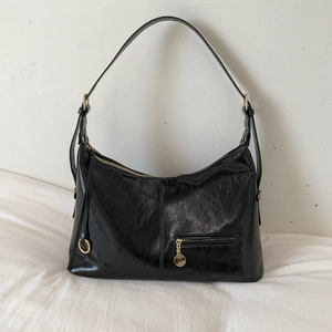 Detail view of black hobo bag showing oil-wax leather texture and gold hardware zipper