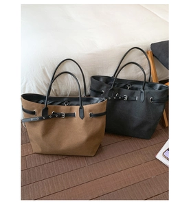 Detail of dark brown and black canvas tote bags with leather straps and metal buckles
