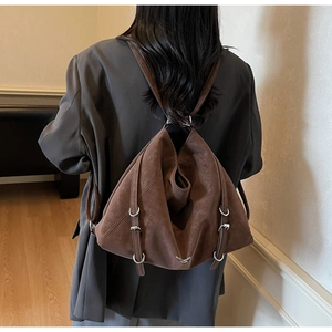 Detail view of brown vintage leather tote bag with unique triangular cut on gray blazer