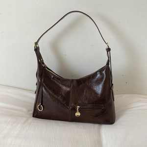 Detail of vintage dark brown faux leather shoulder bag with glossy oil wax finish and gold zip