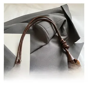 Close-up of leopard print suede bag with adjustable knotted brown leather strap detail