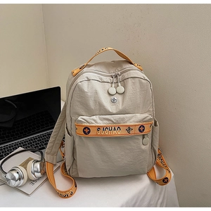 Detail of beige nylon backpack with orange patterned straps and si-chaio logo text