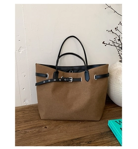 Detailed texture of brown suede tote bag featuring black leather belt and silver metal buckle