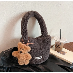 Détail du sac seau en peluche gris foncé avec pendentif ours sur une veste en cuir