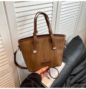 Detailed close-up of brown woven texture and leather handle on the bucket handbag