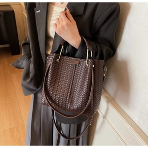 Close-up of luxury dark brown woven texture bucket bag with elegant golden metal handle