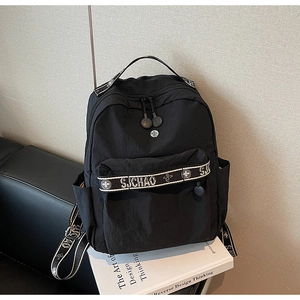 Detail shot of black nylon backpack with SJ CHAO branded straps on a design book