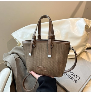 Macro detail of the woven texture and fashion logo on this brown leather bucket bag