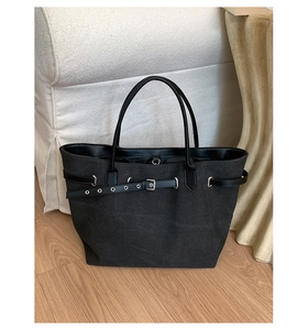 Detailed view of black canvas tote bag with leather straps and silver metal buckles