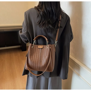 Close-up of brown leather woven bag texture with handles and golden metal buckles
