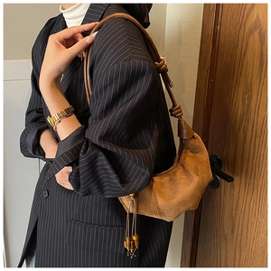 Brown suede croissant bag styled with striped blazer and wooden bead tassels details