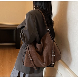 Side view of dark brown tote bag showing silver buckle detail and matte leather texture