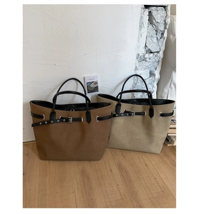 Detail of suede tote bag handles and decorative strap with metallic buckle in caramel brown