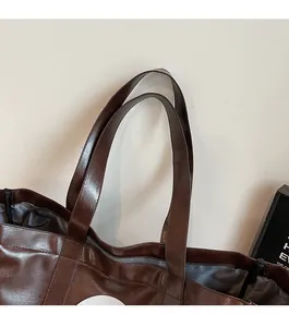 Detailed close-up of the smooth double shoulder straps and brown PU leather texture
