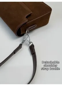Detail of silver metal lobster clasp and stitching on dark brown suede handbag