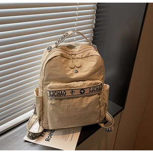 Close-up of beige nylon backpack featuring SJCHAO lettered webbing and side pocket detail