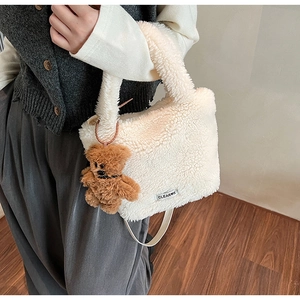 Détail du sac seau en polaire blanc cassé avec breloque ours et étiquette de marque