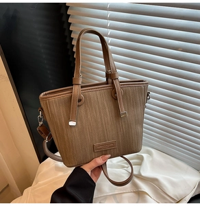 Close-up of brown woven texture handbag with detachable strap and logo detail