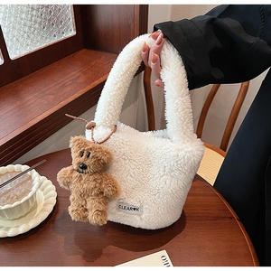 Détail du sac seau en peluche blanche avec un adorable charm d'ours en peluche