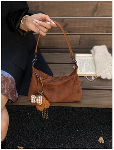 Détail du sac à main marron en daim avec pendentif ours dans un décor d'automne doux