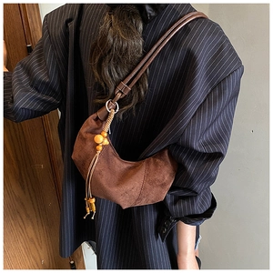 Detail of dark brown suede crescent bag with rope strap and wooden bead tassels