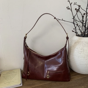 Close-up of burgundy hobo bag with vintage texture and golden metal hardware details