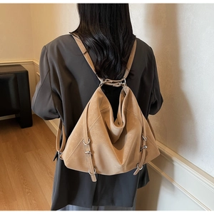 Detail of camel leather tote bag with silver buckles worn by a model in gray blazer