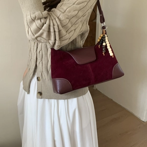 Detail of burgundy hobo bag with matte suede texture and vintage wooden bead tassel