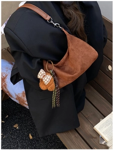 Détail du sac dumpling en daim marron avec pendentif ours en peluche et cordon tressé