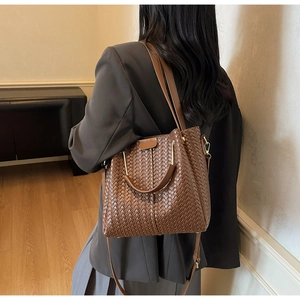 Detail shot of brown woven tote bag showing leather texture and adjustable strap