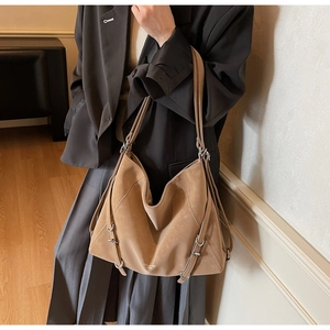Detailed side view of brown faux suede tote bag with silver buckle and branding