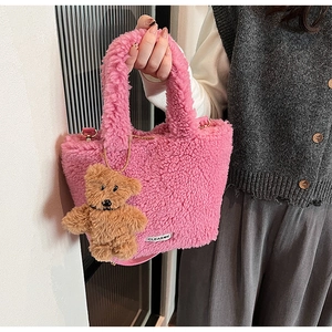 Détail d'un sac seau en peluche rose avec un charm ours brun et étiquette de marque