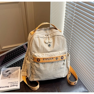 Detail of off-white nylon backpack with orange patterned straps on a leather background