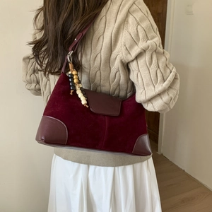 Detail of burgundy faux suede shoulder bag featuring ethnic wooden beaded charm