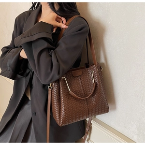 Detailed shot of brown woven leather texture and gold hardware on a luxury tote bag