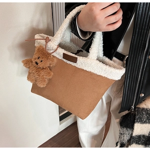 Close-up of brown suede tote bag with white faux shearling trim and bear charm accessory