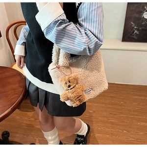 Détail du sac seau en polaire beige avec breloque ours et texture d'étiquette tissée