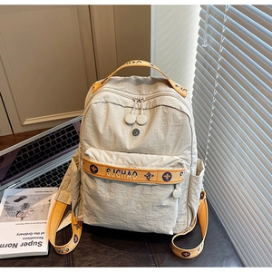 Close-up of cream backpack with yellow jacquard straps and SI JIAO branding details