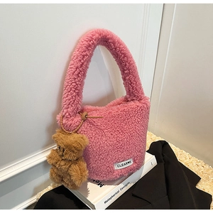 Détail du sac seau rose en peluche avec breloque petit ours brun et étiquette logo
