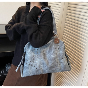Vue détaillée du grand sac cabas bleu avec clous argentés et franges en cuir sur le mannequin