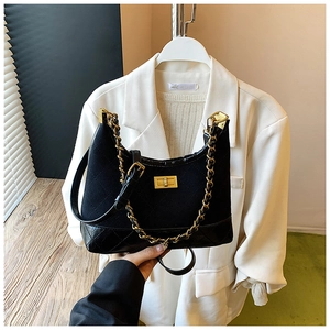 Detail of black quilted crossbody bag featuring gold chain and metallic twist lock closure