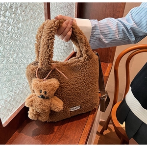 Gros plan du sac en peluche marron avec étiquette de marque et bandoulière réglable