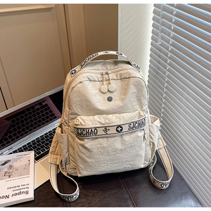 Detail of a beige nylon backpack featuring floral SJCHAO printed straps and zipper pockets