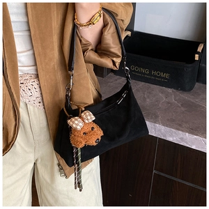 Détail du sac à bandoulière en daim noir avec pendentif peluche ours brun sur la sangle