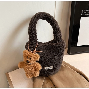 Détail du sac seau en peluche marron avec pendentif ours et étiquette de marque